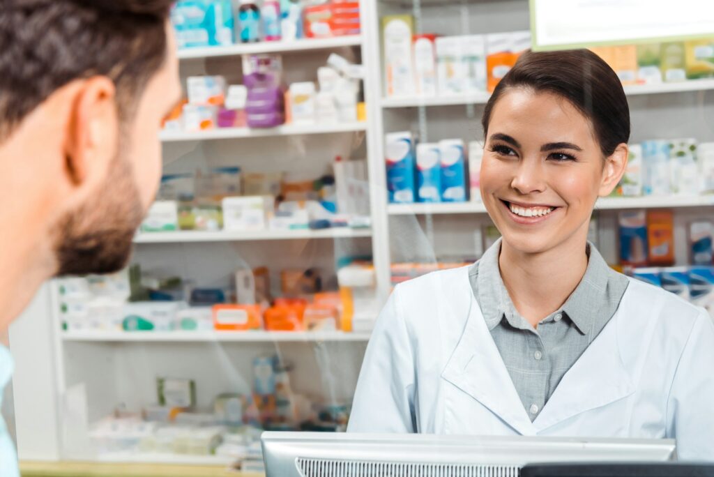 Selective focus of druggist smiling to customer at pharmacy counter