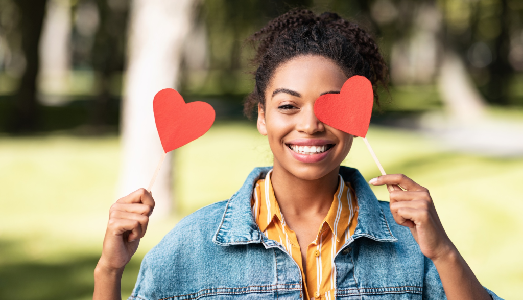 SACC Career Center student smiling outdoors holding paper heart cutouts for campus event