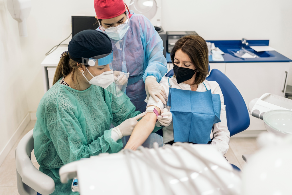 Healthcare professionals drawing blood from a patient in a medical clinic setting