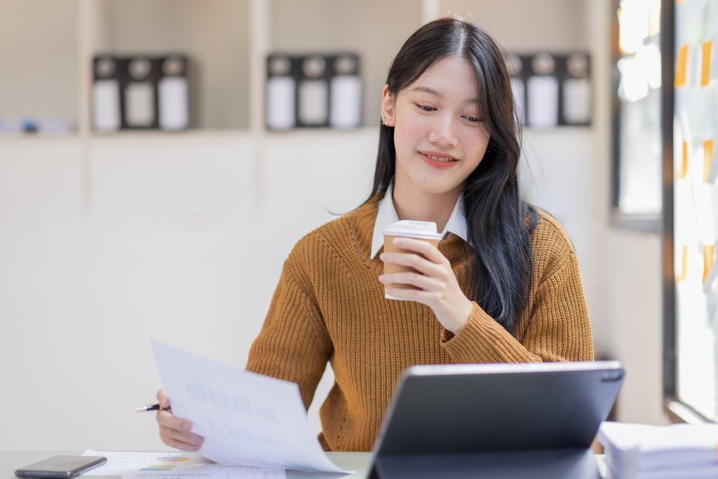 SACC Career Center student reviewing financial documents with coffee while studying on laptop